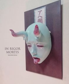 a blue mask with horns sticking out of it's mouth on a wall mounted plaque