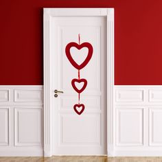 an open door with two hearts hanging from it's side, in front of a red wall