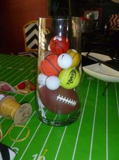 a glass filled with balls sitting on top of a green table covered in white stripes