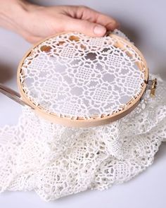 someone is holding a wooden hoop with white lace on it