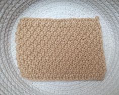 a crocheted dishcloth on a white plate with a brown square in the middle