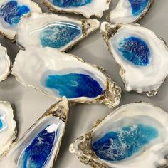 several blue and white oysters are arranged on a silver surface with water in the middle