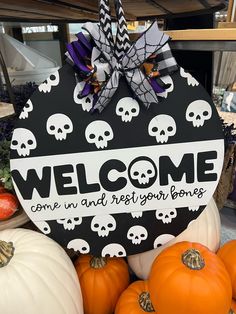 a welcome sign is surrounded by pumpkins and other halloween decorations in a store display