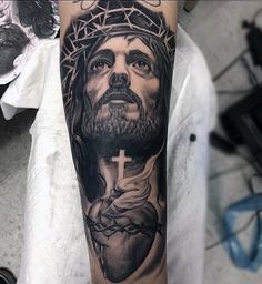 a man's arm with a tattoo of jesus on it and a cross in the center