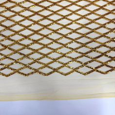 gold sequins on white fabric with small squares in the center and diagonal lines