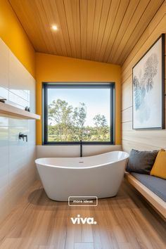 a large white bath tub sitting under a window next to a wooden floored wall