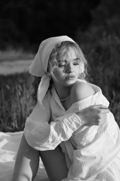 a black and white photo of a woman sitting on the ground with her eyes closed