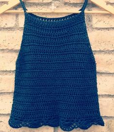 a blue crocheted top hanging on a brick wall