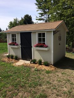 a small shed with flowers in the window boxes