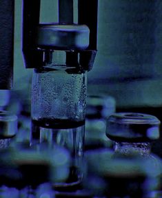 water is being poured into a glass container with several other containers in front of it