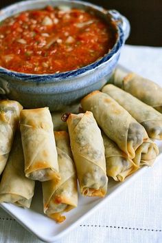 some food is sitting on a plate with a bowl of sauce in the middle and another dish next to it