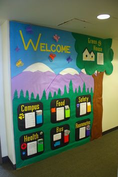 a welcome sign is on the wall in an office building with trees and mountains painted on it