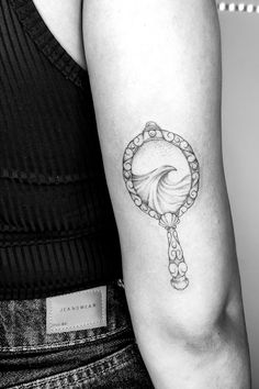 a black and white photo of a woman's arm with a tattoo on it