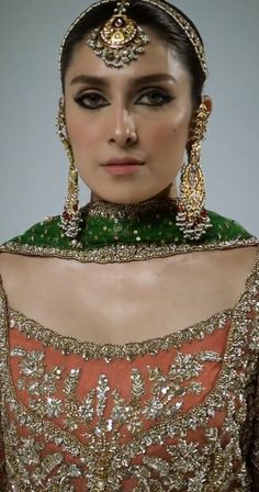 a woman in an orange and green dress with gold jewelry on her head, wearing a tiara