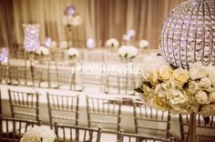 the tables are set up with white flowers and crystal vases for centerpieces