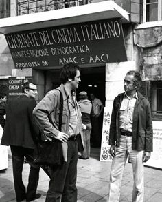 black and white photograph of two men standing in front of a building with signs on it