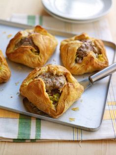 four pastries on a tray with a fork and plate in the background, ready to be eaten