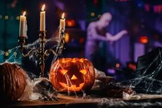 a halloween pumpkin sitting on top of a table with two candles in front of it