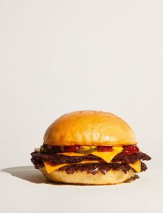 a cheeseburger with bacon, lettuce and tomato on a white background