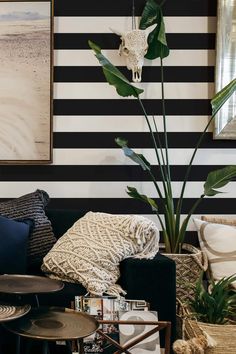 a living room with black and white stripes on the wall, plants in vases