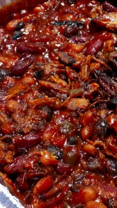 a large casserole dish with meat and beans in it on a red checkered table cloth