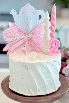 a white cake with pink icing and a tea cup on top