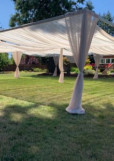 an outdoor wedding venue with white drapes on the grass and trees in the background