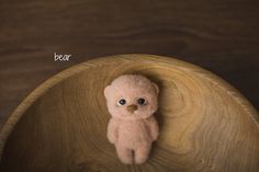 a small teddy bear sitting on top of a wooden bowl with the word bear written above it