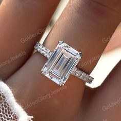 a woman's hand with an emerald and diamond ring on it