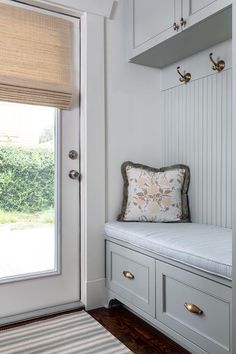 a white bench sitting under a window next to a door