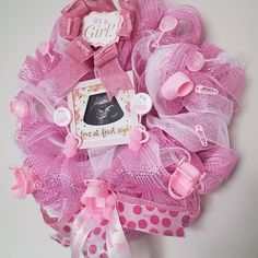 a pink mesh wreath decorated with baby items