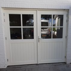 two white double doors with glass on the outside and brick wall in front of them