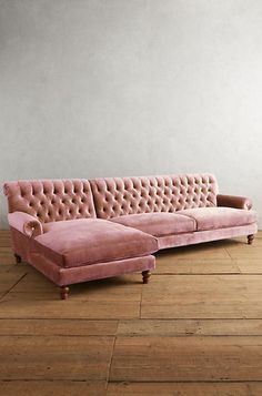 a pink couch sitting on top of a hard wood floor next to a white wall