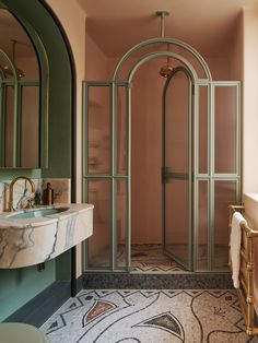 a bathroom with a glass shower door and marble counter top, along with a sink