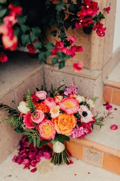 a bouquet of flowers sitting on the ground next to some steps with pink and orange flowers