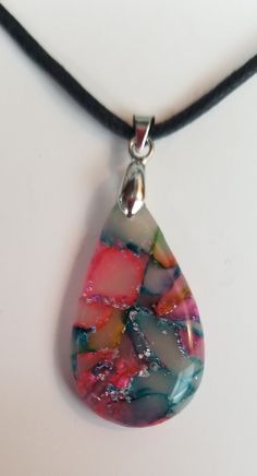 a necklace with a glass pendant hanging from it's side on a black cord