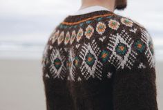 a person standing on the beach wearing a sweater