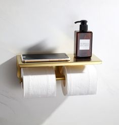 two rolls of toilet paper sitting on top of a shelf next to a phone and soap dispenser