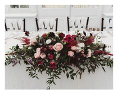 an arrangement of flowers and greenery on a white table cloth at a wedding reception