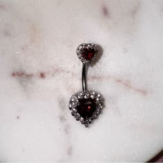 a pair of heart shaped danglings on a marble surface with crystals in the center