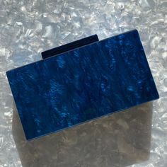 This acrylic party box clutch features a hand swirled acrylic exterior in a mesmerizing blue. Push open the matching acrylic top clasp and inside you will find a black lined interior. Comes with optional gold-toned crossbody chain to carry as a shoulder bag or you can add one of our acrylic chains for even more style. Fits an iPhone Plus with case. ▪️Length: 7.25", Height: 3.75", Depth: 1.75" ▪️Materials: acrylic, plated metals, cotton/polyester lining. Small variations can happen in the product Modern Blue Clutch For Formal Occasions, Trendy Blue Clutch For Formal Occasions, Trendy Blue Evening Clutch, Blue Rectangular Clutch For Events, Blue Rectangular Clutch For Formal Occasions, Trendy Blue Clutch For Gift, Blue Rectangular Clutch For Evening, Acrylic Clutch, Party Box