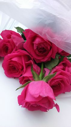 a bouquet of pink roses sitting on top of a white tablecloth covered table cloth