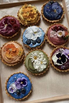 nine pies with flowers on them sitting in a wooden box next to each other