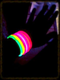 a person's arm with glowing bracelets on it