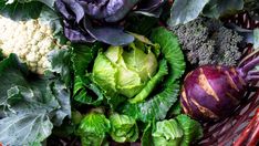 a basket filled with lots of green and purple vegetables next to broccoli florets