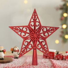 a red christmas tree topper sitting on top of a table next to other decorations