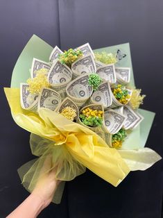 a bouquet made out of dollar bills is being held by a person's hand