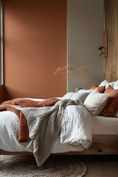 a bed sitting in a bedroom next to a window with brown and white blankets on it