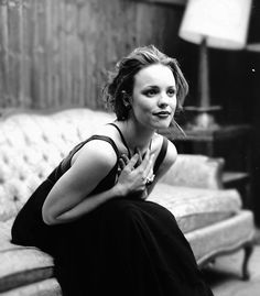 a woman sitting on top of a couch next to a lamp