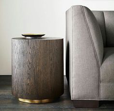 a grey couch sitting next to a wooden table on top of a hard wood floor